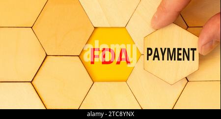 FDA Food and Drug Administration payment symbol. Concept words FDA payment on beautiful wooden puzzle. Beautiful yellow table background. Businessman Stock Photo