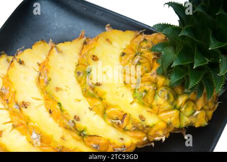 Ripe vibrant pineapple sliced on a black plate Stock Photo