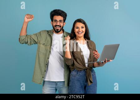 Excited young indian couple holding and using laptop Stock Photo