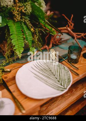 Boho style table setting with a blank card decorated with fern branches close up, Wedding Mockup. Romantic table with paper invitation card. Stock Photo