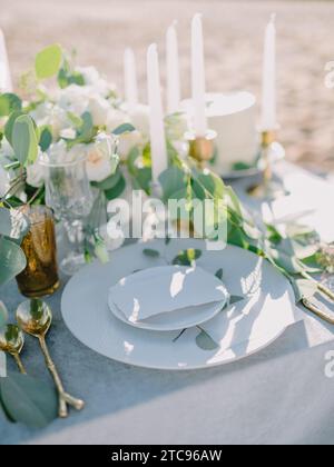 Elegant table setting with a paper card decorated with eucalyptus branches close up. Romantic table with paper invitation card. Wedding Mockup. Stock Photo
