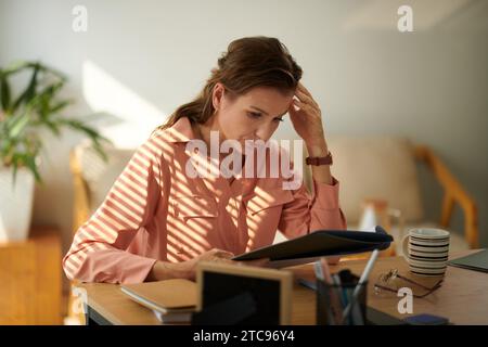 Serious focused mature businessman reading marketing research report Stock Photo