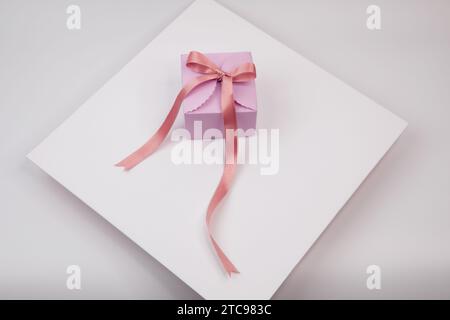 A picture of a pink present, wrapped in a white ribbon bow, on a crisp white background Stock Photo