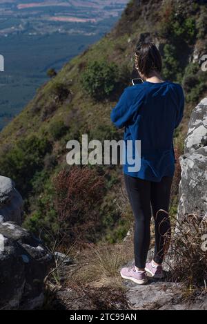 Young lady dressed in casual sportswear out hiking taking a picture with her cell phone Stock Photo