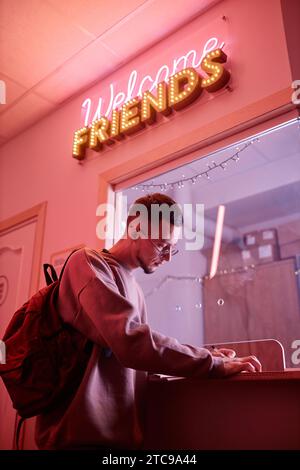 Side view portrait of young student signing in to register in hostel or college dorm, copy space Stock Photo
