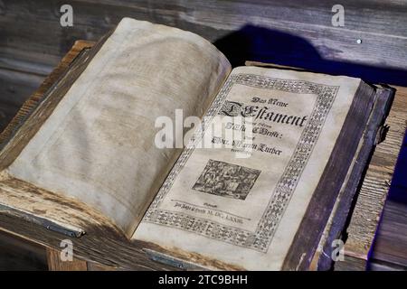An opened very old bible sitting on top of a old wooden table Stock Photo