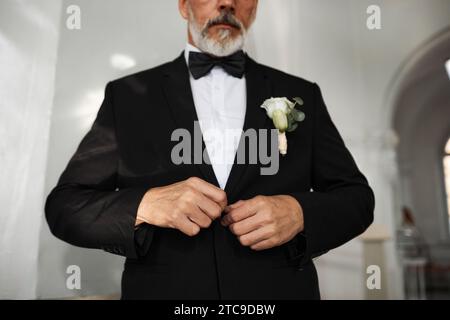 Cropped waist up image of senior man as groom dressing in suit and buttoning jacket for ceremony in church, copy space Stock Photo