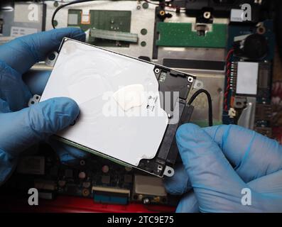 Technician installing hard disk to computer. Removing or plugging in disk cable. Data recovery concept background. Stock Photo