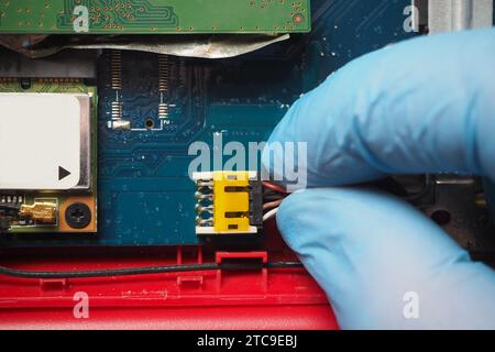 Technician plugging 8-pin data and power cable to the connector on electronic circuit board. Hand plugs cable into socket on main board. Stock Photo