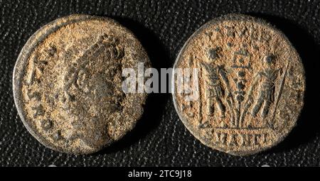 Ancient Roman coin of Emperor Constantius II, top view of vintage metal money isolated on black background. Theme of old grungy copper texture, Rome, Stock Photo