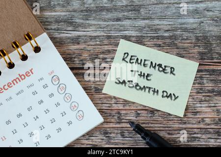 Remember the Sabbath Day, handwritten verse on note and calendar on wooden table. Christian holy time, obedience, rest, and worship God Jesus Christ. Stock Photo