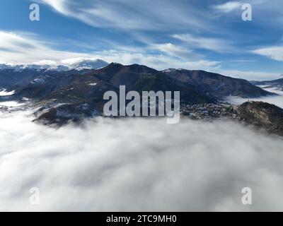 A stunning winter landscape featuring snow-covered mountains and vast, moody clouds above them Stock Photo