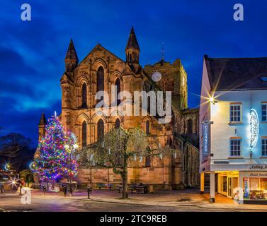 An external view at dusk at Christmas of Hexham Abbey in Northumberland floodlit with a Christmas tree Stock Photo