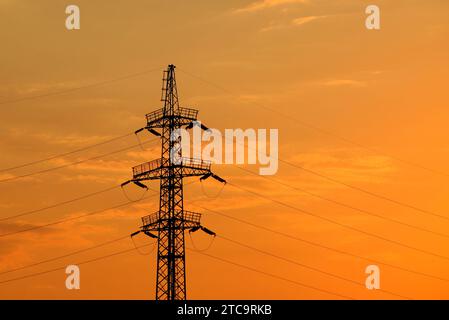 High voltage electricity line in Ukraine On Sunset. Concept of Russian missile attack on Ukrainian energy during war. Blackout, saving energy, light. Stock Photo