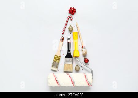 Christmas tree made of painter's tools and decorations on light background Stock Photo