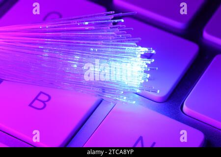 Optical fiber strands transmitting color light on computer keyboard, macro view Stock Photo