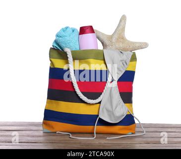 Stylish bag with starfish and other beach accessories on wooden table against white background Stock Photo