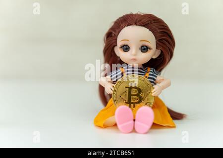 Digital Currency of The Future. Selective focus of a doll on the knee holding bitcoin replica. Bitcoin Cryptocurrency. Stock Photo