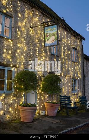 Christmas lights on The Swan pub at dusk. Southrop. Cotswolds, Gloucestershire, England Stock Photo