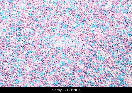 Colorful sprinkles made of tiny sugar balls. Mix of purple, blue, rose and white nonpareils. Decorative edible Hundreds and Thousands made of sugar. Stock Photo
