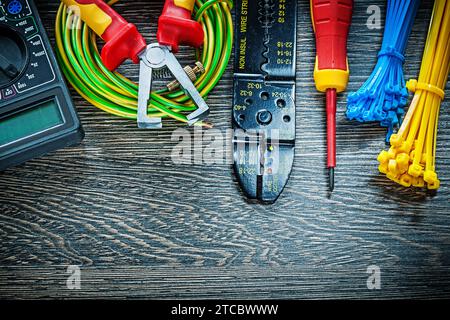 Electric tester Screwdriver Rolled cable ties Wire stripper on wooden board Stock Photo