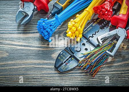 Electrical tester Wires Cable ties Bolt cutters Wire strippers Insulation pliers Insulation screwdriver on wooden board Stock Photo