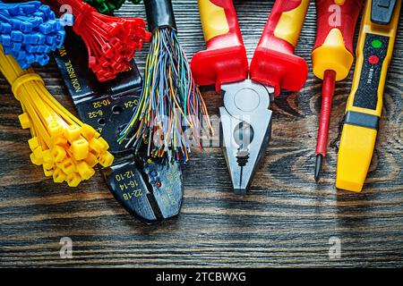 Electrical tester Cable ties Bolt cutters Pliers Insulation screwdriver on wooden board Stock Photo