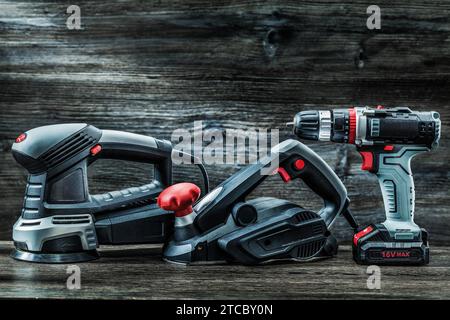 Electric hand tools Orbit wood sander planer and cordless drill driver on vintage wood Stock Photo