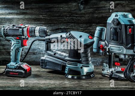 Electric hand tools Orbit wood sander plunge router router and cordless drill driver on vintage wood Stock Photo
