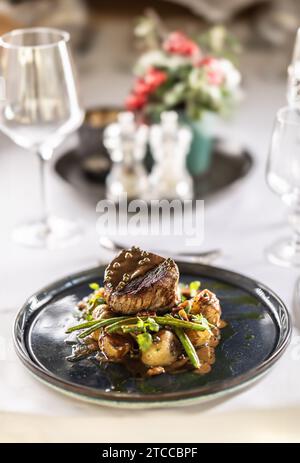 Fillet steak from beef tenderloin, sautéed green beans with bacon, baked potatoes and green pepper sauce. Fillet steak served on a plate on a festive Stock Photo