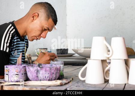 Fez, Morocco: Moroccan artisan painting ceramic cups and mugs inside a workshop in Fes Medina. Stock Photo