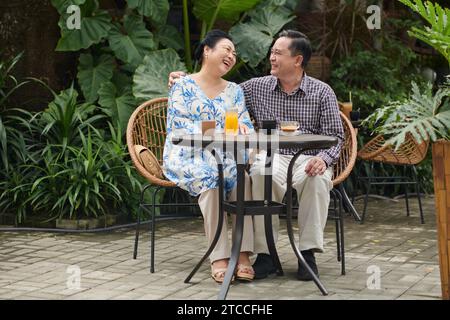 Happy senior couple spending time in outdoor cafe, enjoying drinks and conversation Stock Photo