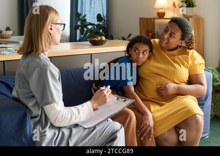 Nurse visiting to sick child at home, she talking to her mother and prescribing the medicine Stock Photo