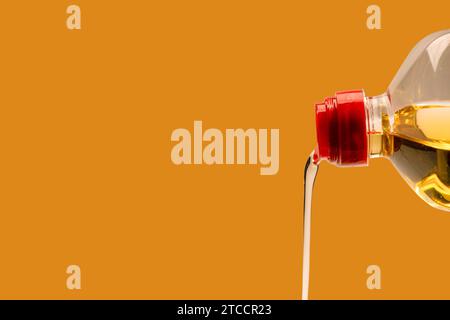 A bottle of sunflower oil isoalted on an orange background. Oil pouring from a bottle. Stock Photo