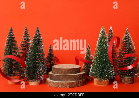 Festive Christmas scene podium for products showcase, promotional sale, green Christmas trees with wooden podium on red background Stock Photo