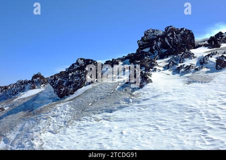 volcanic rock and frozen snow on Mount Etna North-East Crater in winter, Sicily, Italy Stock Photo