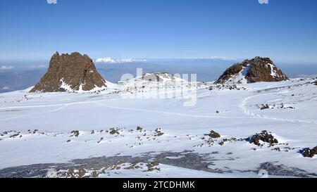 optical illusion of inactive volcano between 'I Due Pizzi' or 'Frati Pii' hornitos on snow covered mountainside of Mount Etna North-East Crater, Sicil Stock Photo