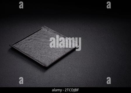 Square empty ceramic plate on textured concrete background. Kitchen utensil item Stock Photo