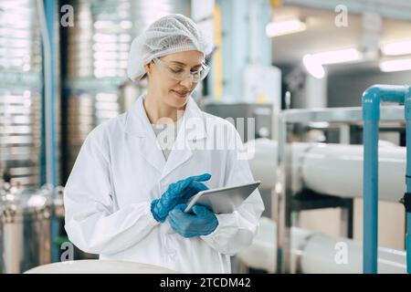 Happy senior science staff women worker work control quality of water in drinking water plant using tablet to record jobs. Stock Photo