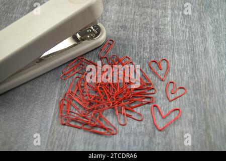 stapler with red paper-clips, three of them heart-shaped, love in the office Stock Photo