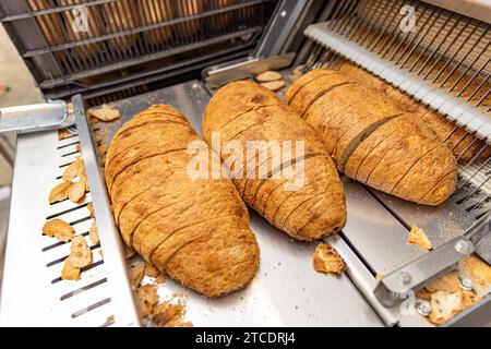 Freshly baked loaves of bread in a bakery sliced for sale - industrial food production Stock Photo