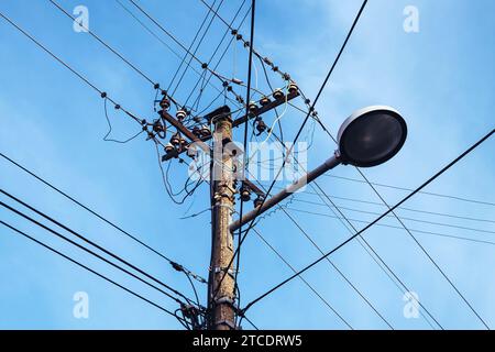 Street light with electricity utility pole and messy electrical wires, low angle view Stock Photo