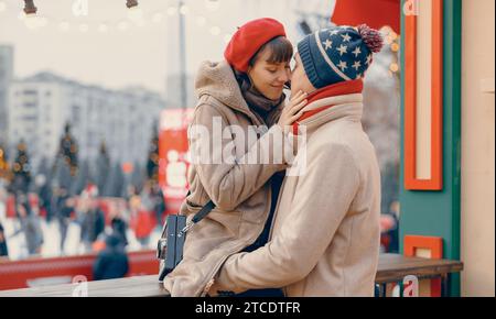 Tender moment between a couple at a Christmas market, surrounded by holiday lights Stock Photo