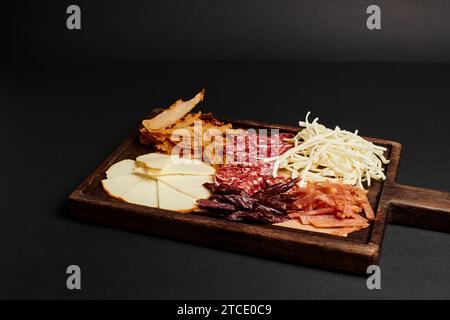 charcuterie board with cheese selection, dried beef and salami slices on wooden cutting board Stock Photo