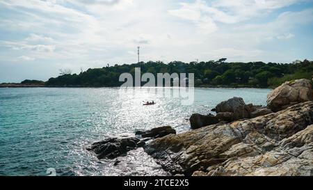 Scenic view of friends sea kayaking in the morning. View from the rock cliffs of kayaker exploring the crystal clear waters of a cove off the coast of Stock Photo