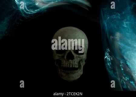 Skull on a black background adorned with dynamic blue-turquoise light painting arcs. The arcs were created using an illuminated crumpled plastic bottl Stock Photo