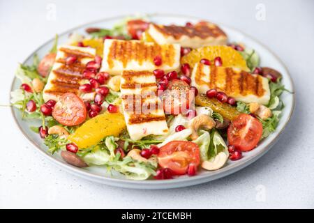 Warm salad with fried halloumi cheese, nuts (cashews and almonds), cherry tomatoes, pomegranate, orange and arugula. Traditional cheese of the Eastern Stock Photo