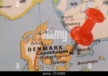 A red pin stuck into a map of Western Europe, pinpointing the location of Copenhagen Stock Photo