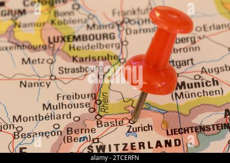 A red pin stuck into a map of Western Europe, pinpointing the location of Zurich Stock Photo