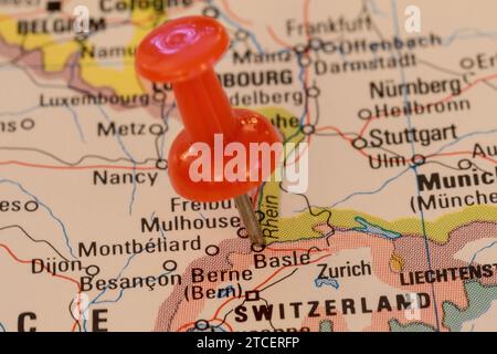 A red pin stuck into a map of Western Europe, pinpointing the location of Basle Stock Photo